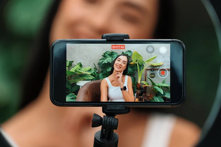 Young woman making beauty and cosmetic tutorial video content. Blithe influencer